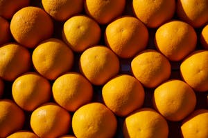 Top-down view of fresh organic oranges arranged closely in a vibrant pattern.